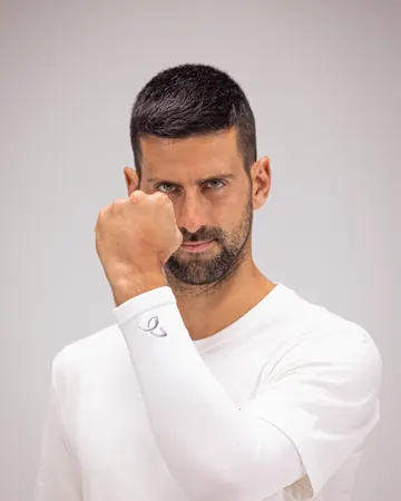 Nærbilde av Novak Djokovic med knyttet neve og logoen hans på den hvite Arm Sleeve