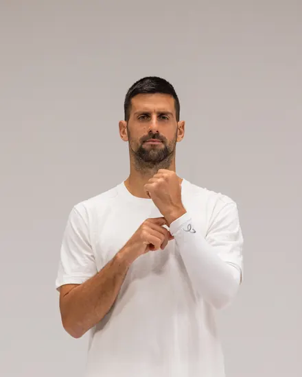 Novak Djokovic drar en hvit Arm Sleeve på plass