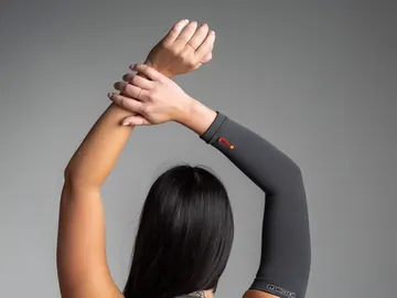 Armstrømpe (Arm Sleeve) i fargen Charcoal, på en arm som strekkes over hodet