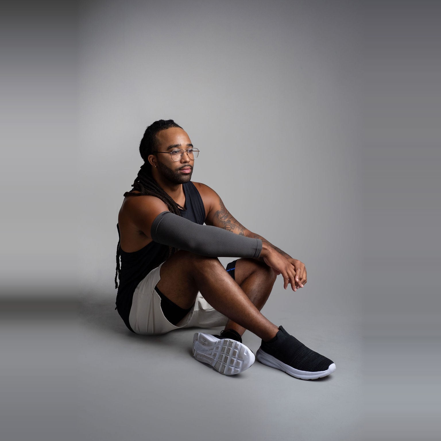 Mørkegrå Arm Sleeve (Charcoal) på en mann som sitter