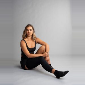 Kvinne som sitter på gulvet med sort Leg Sleeve